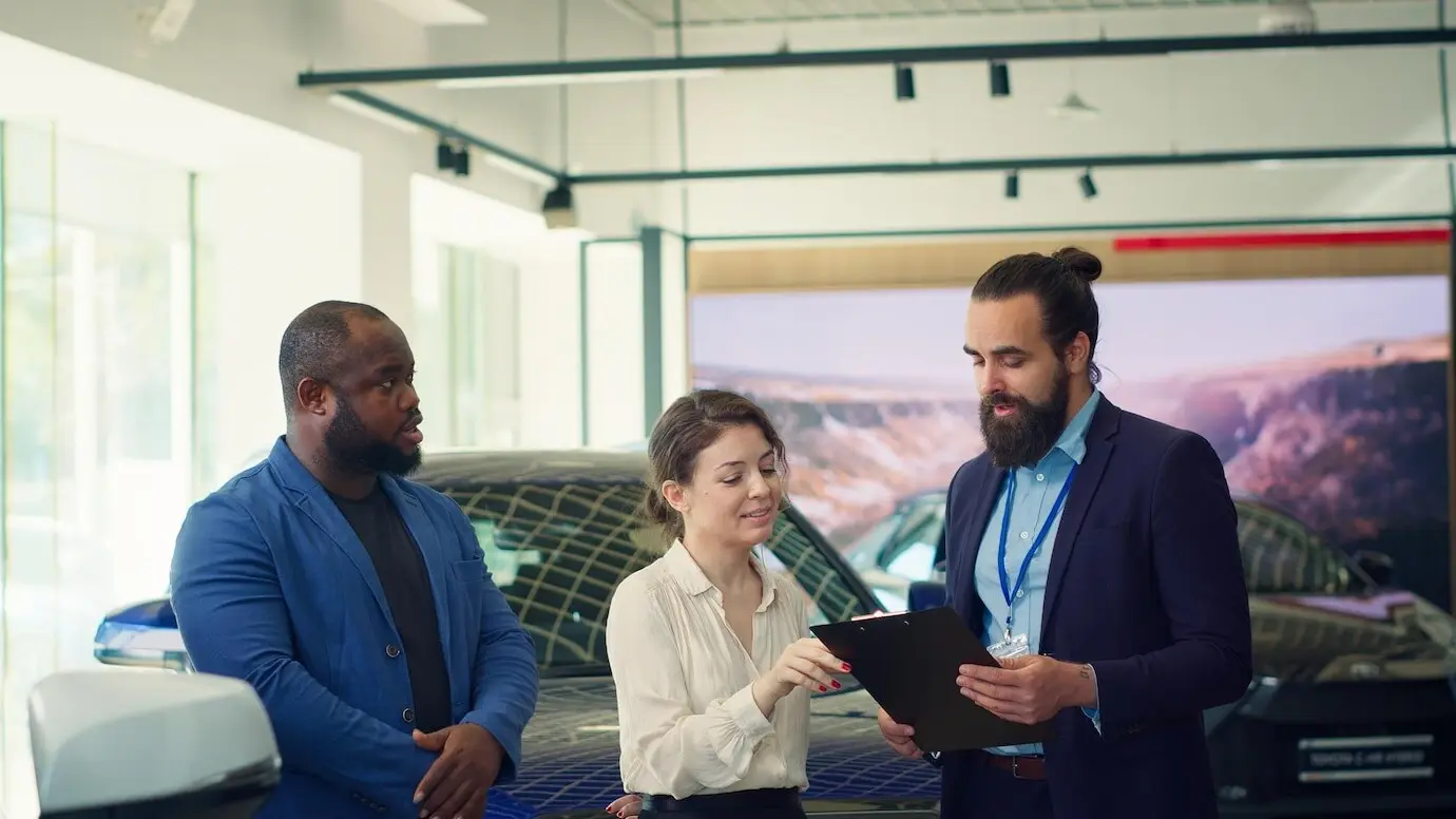 Un vendedor de un concesionario de automóviles haciendo preguntas a los clientes.